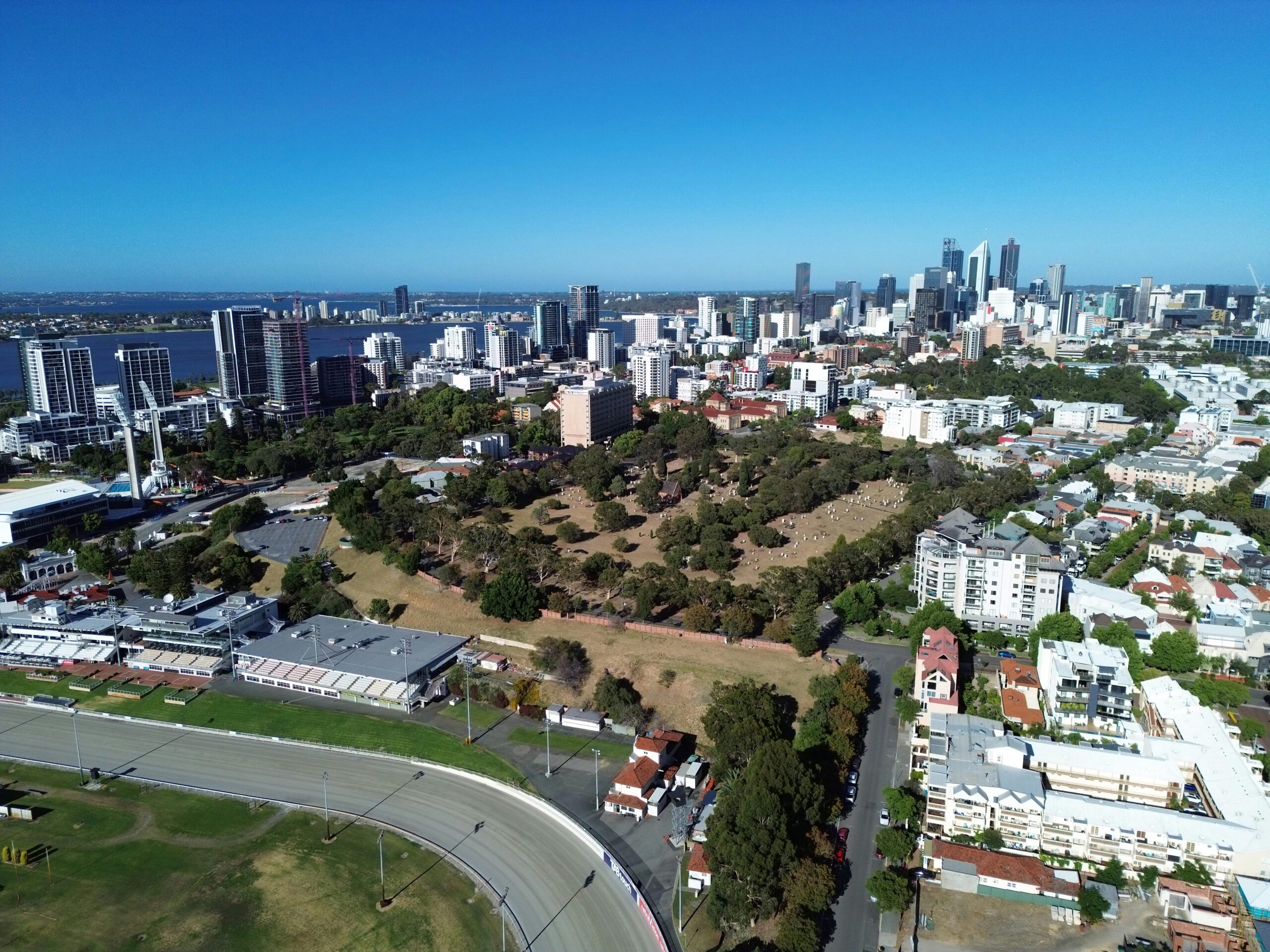 Stunning aerial shot showcasing Perth city skyline, parks, and river in sunny daylight.